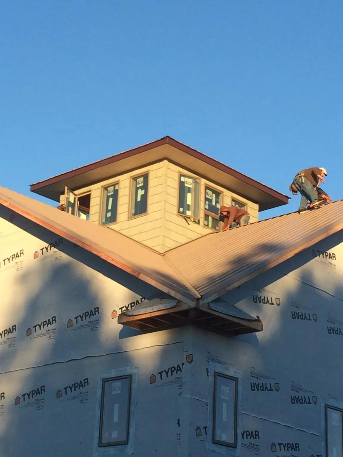Roofers working around a rooftop cupola on a new metal roof at sunset — Roof Waterproofing in Lindon by Roofing Brothers